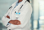 Body of doctor in the hospital cropped. Confident doctor arms crossed in the hospital. African american doctor wearing a badge in the clinic. Closeup of caring doctor arms crossed