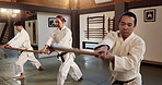 Students, stick or learning martial arts in dojo for physical practice, aikido movement or self defense. Combat demonstration, Japanese people or training workout for fighting, education or class