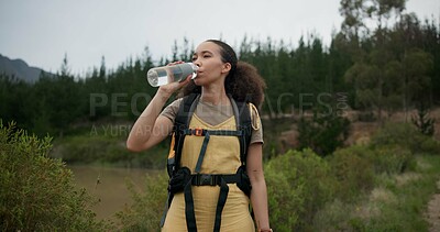 Hiking woman, drinking water and bottle in forest for hydration, detox or wellness on bush adventure. Girl, trekking and liquid for health in nature, woods and outdoor for fitness, exercise or summer