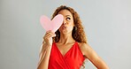 Woman, love and kiss face with paper heart for opinion, romance or thinking with ideas on grey background. Face, emoji and female person with happiness for kindness, vote or support on valentines day