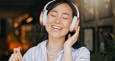 Happy asian woman, headphones and listening to playlist music in cafe for audio streaming, dancing or singing. Female person or freelancer smile or enjoying podcast, sound or song at coffee shop or restaurant