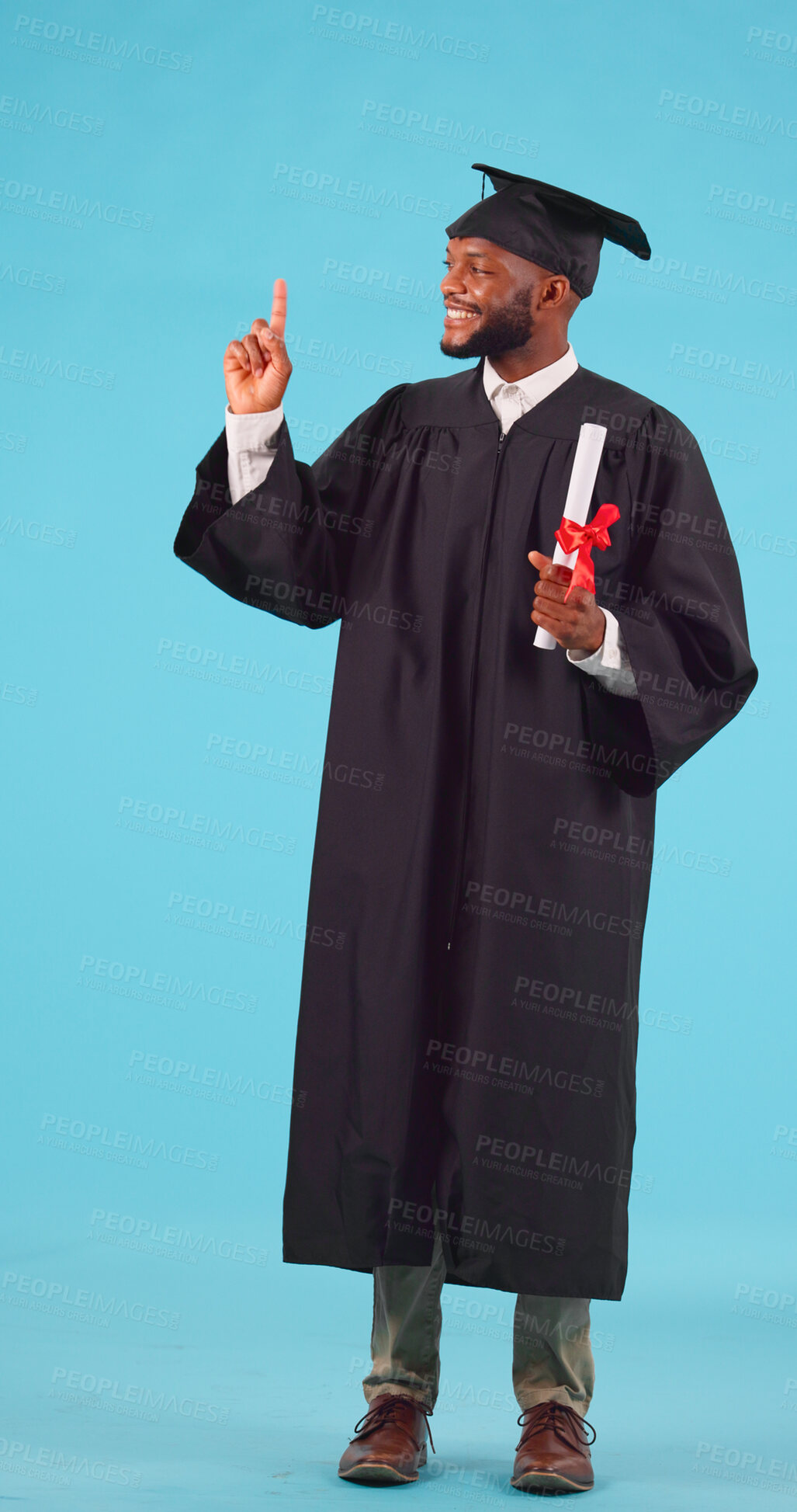 Buy stock photo Black man, graduation and point up for education achievement, university advertising and diploma on blue background. Success, future and certified, academic course promotion and graduate in studio 