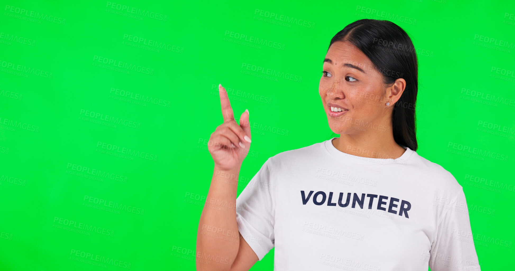 Buy stock photo Pointing, volunteer and happy Asian woman on green screen for charity announcement, news and information. NGO, mockup and person with hand gesture for non profit, community service and help in studio