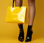 Woman, legs and handbag in studio for accessories, fashion or classy style on isolated yellow background, Luxury, leather and female model with heels for designer purse, trendy tote bag or product