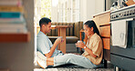 Talking, coffee and a happy couple at home with love, care and communication. Young woman and man laughing while drinking tea together to bond for happiness, quality time and conversation on a floor