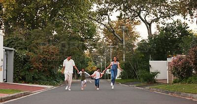 Family, parents and kids in street, skipping and playful with love, care or holding hands in neighborhood. Happy man, woman and children with funny walk, excited and playing outdoor in road in summer