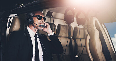 Buy stock photo Shot of a mature businessman using a headset while traveling in a helicopter