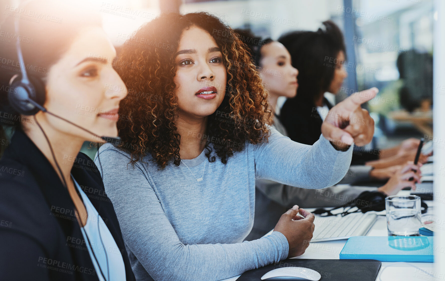 Buy stock photo Shot of a young woman assisting her colleague in a call centre