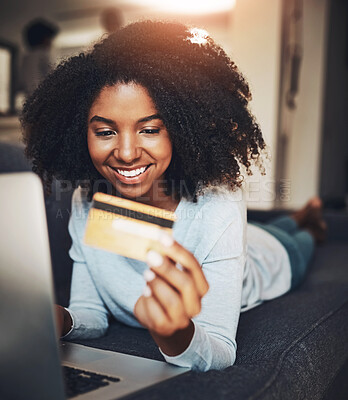 Buy stock photo Shot of an attractive young woman using a laptop and a credit card at home