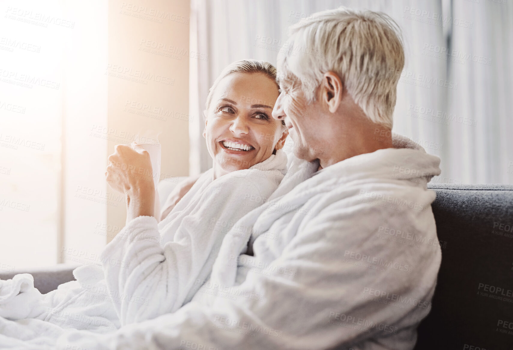 Buy stock photo Mature couple, sofa and relax with coffee in gown or robe for luxury spa day together at resort. Senior man or woman with smile for morning, beauty or relaxation treatment on holiday getaway in suite
