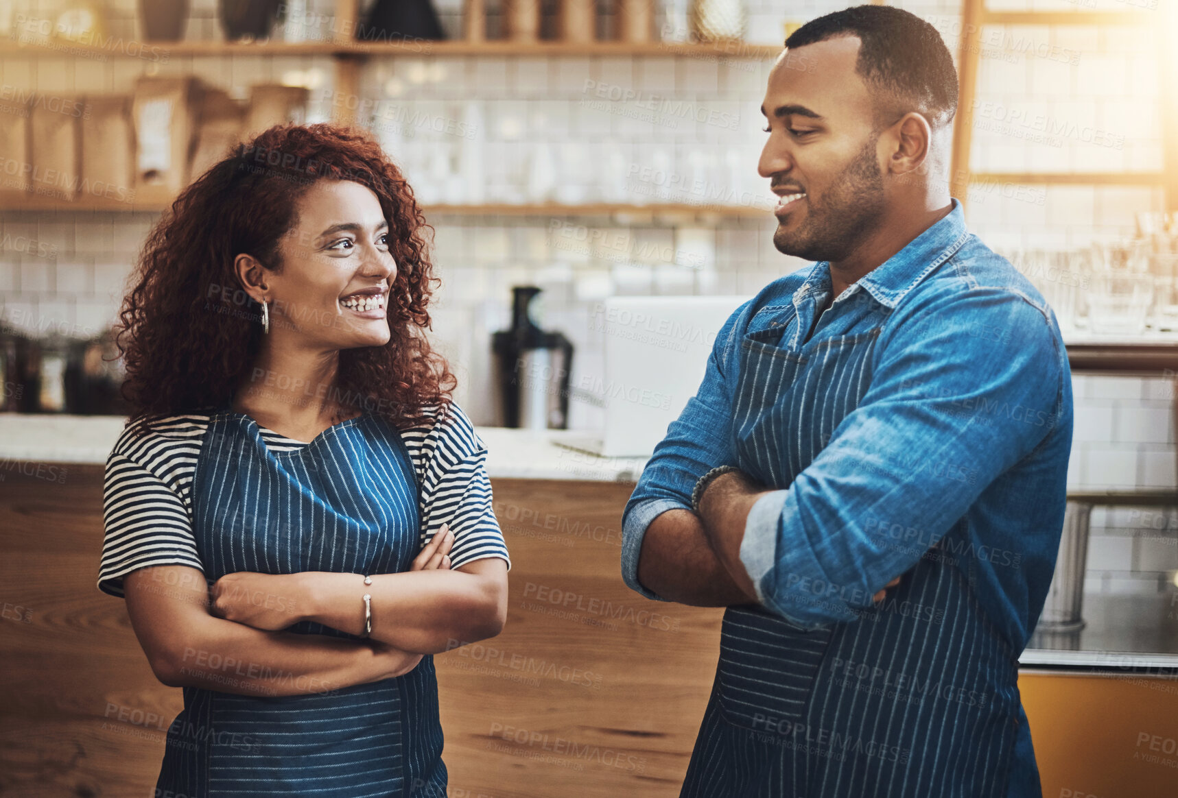 Buy stock photo Cropped shot of an affectionate young couple standing with their arms crossed in their coffee shop