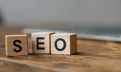 Wood, building blocks and SEO text on table in closeup for web traffic, letters or toys for company growth. Cube, words and language with search engine tools for internet on desk at creative agency