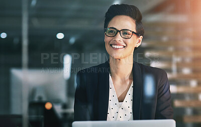 Buy stock photo Shot of a confident businesswoman working on a laptop in an office at night