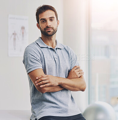 Buy stock photo Cropped portrait of a male physiotherapist sitting with his arms folded in his office