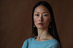 Serious, business and portrait of Asian woman in studio for career, pride and confidence in job. Journalist, female person and face of reporter for production, hosting and media on brown background