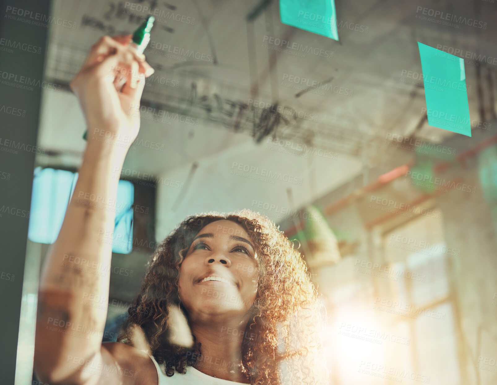 Buy stock photo Shot of a focussed young businesswoman putting up sticky notes on a glass wall while brainstorming in the office at work