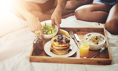 Buy stock photo High angle shot of an unrecognizable couple enjoying breakfast in bed together at home
