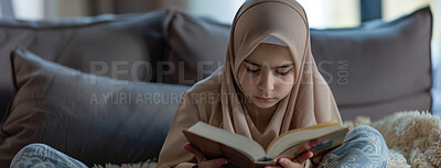 Buy stock photo Muslim, religion and kid reading Quran in home on sofa for faith or worship on EID in living room. Islam, girl and child study book for learning, education or spiritual knowledge on ramadan mubarak