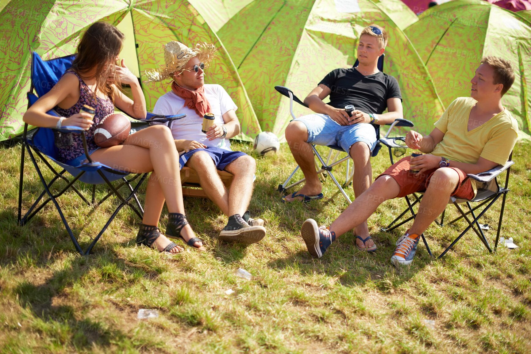 Buy stock photo Camping, group of friends in conversation at tent and relax with outdoor chat, drinks and grass. Nature, men and woman at campsite together for music festival, adventure and people bonding in park.