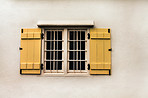 Window, yellow shutters and vintage house with white walls and metal bars for safety or security. Real estate, residence and retro building with an exterior window frame of an old house or cottage.