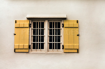 Buy stock photo Window, yellow shutters and vintage house with white walls and metal bars for safety or security. Real estate, residence and retro building with an exterior window frame of an old house or cottage.