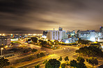 City, lights and urban landscape of a road, street and building at night with infrastructure. Cityscape architecture, skyscraper and skyline background outdoor with buildings and city street lighting