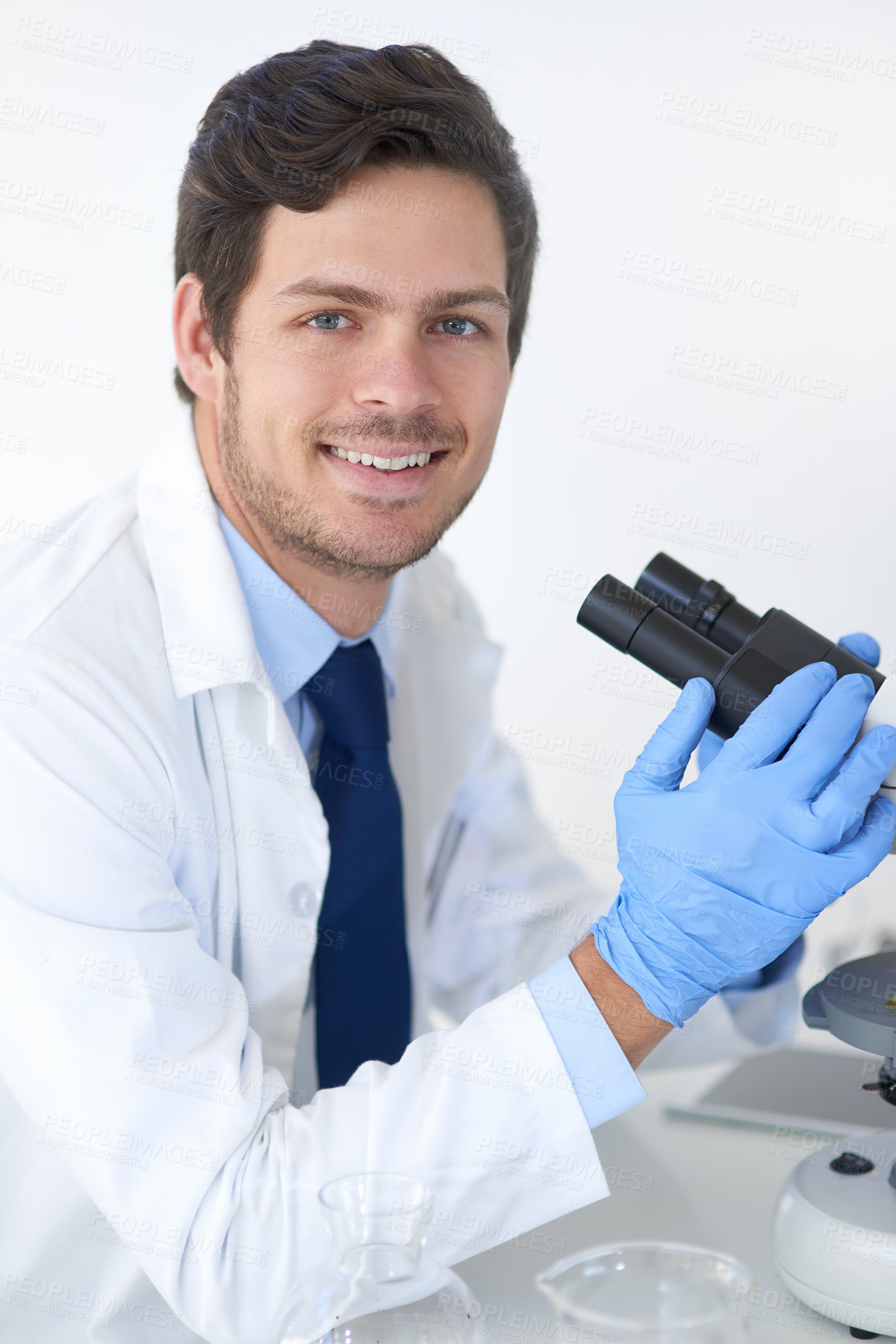 Buy stock photo Happy, scientist and portrait in lab with microscope for medical study, steam cell research and investigation. Smile, man and experiment for biotech science, innovation and development of vaccine