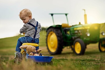 Buy stock photo Child, bike and teddy bear in countryside for development, farming and toys on lawn. Tractor, young boy and outdoor for springtime, growth and learning in nature or field with truck for agriculture 