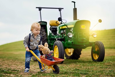 Buy stock photo Child, teddy bear and wheelbarrow on farm for development, nature and tractor in countryside. Truck, boy and outdoor for springtime, growth and learning in field with toys for motor skills and fun