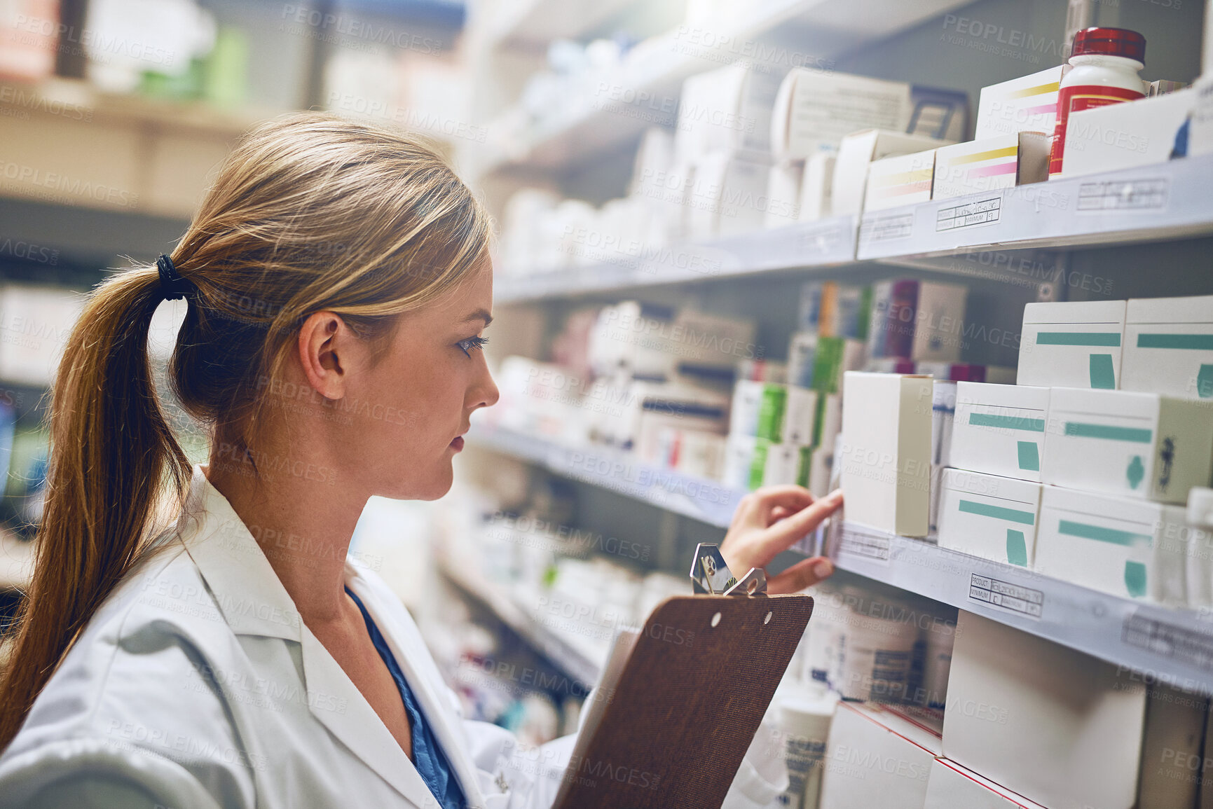 Buy stock photo Shot of a pharmacist looking at medication on a shelf