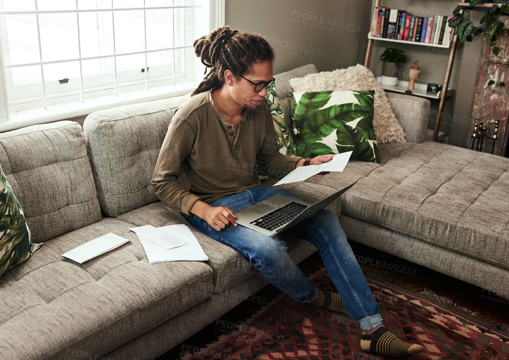 Buy stock photo Finance, laptop and paper with black man on sofa in living room of home for bank or payment. Computer, documents for budget and money with person in apartment for investment, savings or tax audit