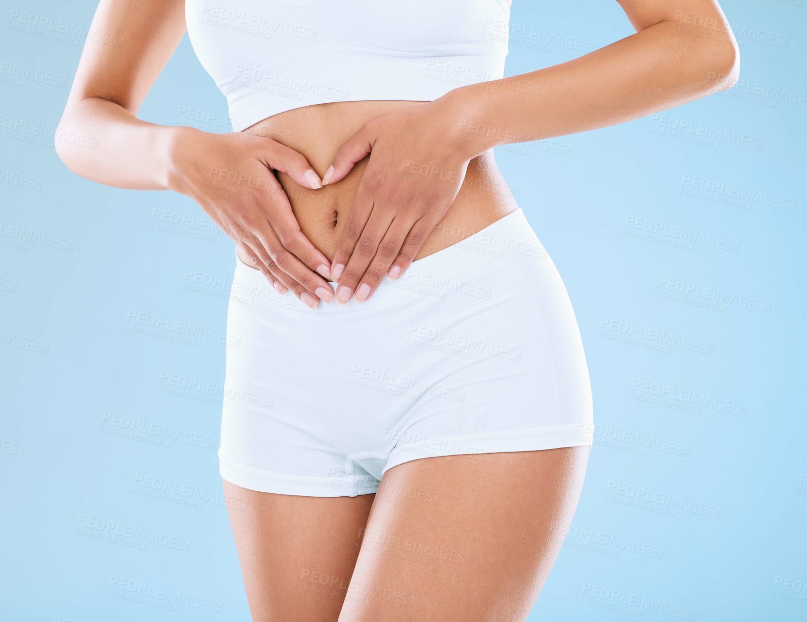 Buy stock photo Girl, heart and hands on stomach in studio for gut health, digestive wellness and nutritional balance for digestion. Woman, love gesture and isolated on blue background for body care and weightloss.