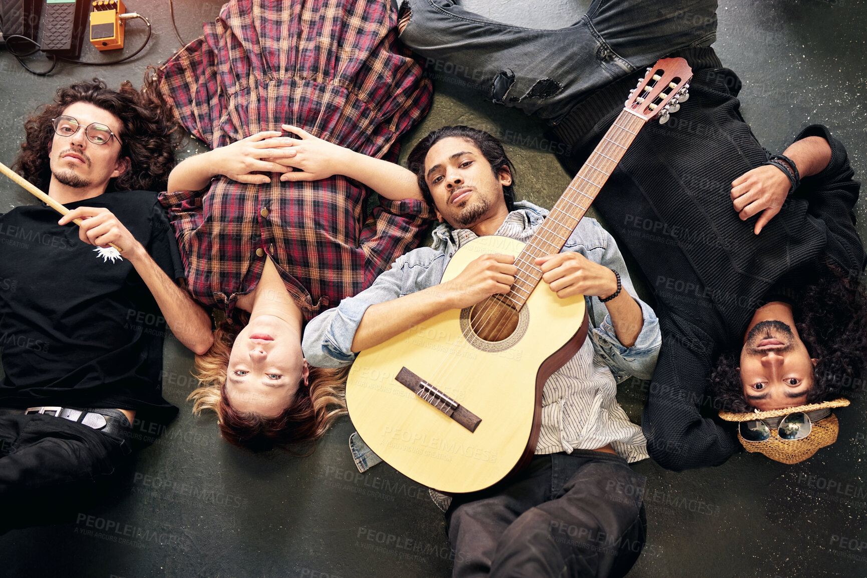 Buy stock photo Above, musician and people in creative band tired on floor after festival, event or relax at gig. Rock, group and man with guitar together with friends on ground in theatre or club for performance