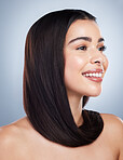 Beautiful brunette woman with healthy skin and hair against a grey background. Young mixed race woman with long brown hair smiling and looking at the camera