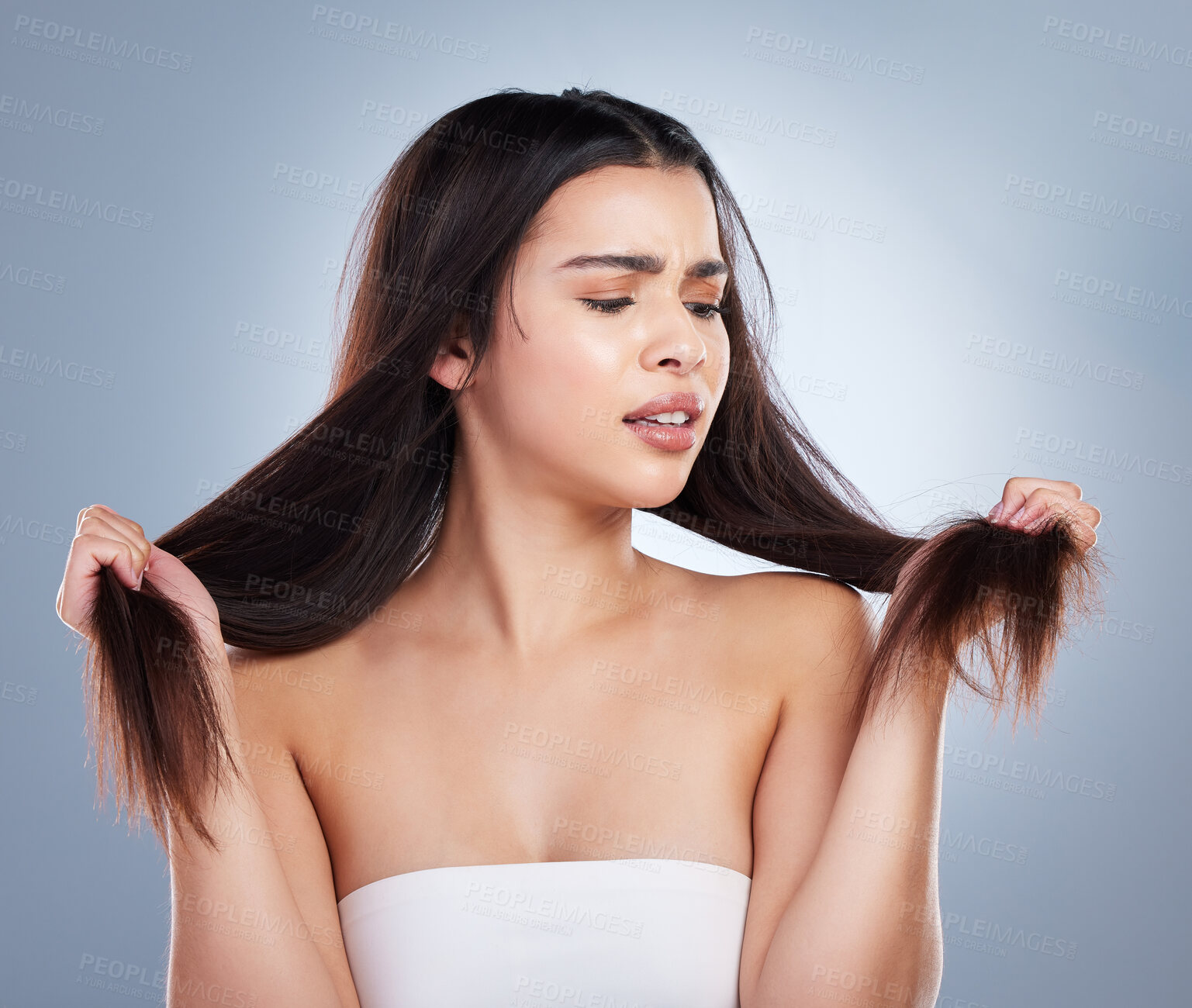 Buy stock photo Upset woman, hair and damage with split ends for disaster or haircut on a blue studio background. Frustrated female person or young model with stress, dry or bristle piece for messy or bad treatment