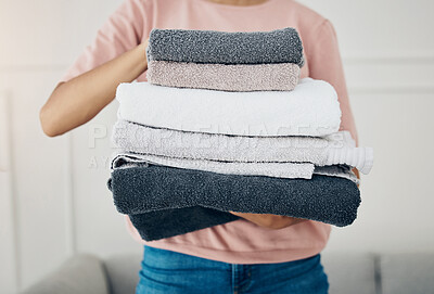 Buy stock photo Towels, laundry and cleaning with a woman housekeeper closeup in the living room of a home for hygiene. Hands, housekeeping and chores with a female cleaner carrying a pile of washing in her house