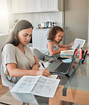 Mother and daughter being productive with remote work and homework, multitasking at a kitchen table at home. Parent and child serious while paying bills and watching an online education programme