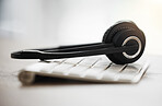 Closeup of headset on a computer keyboard in an empty call centre office. Operating helpdesk for customer service and sales support. Telemarketing agents providing online assistance