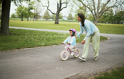 Buy stock photo Kids, bike and a mother teaching her daughter how to cycle in a park while bonding together as a family. Nature, love and children with a girl learning how to ride a bicycle with her mom outside