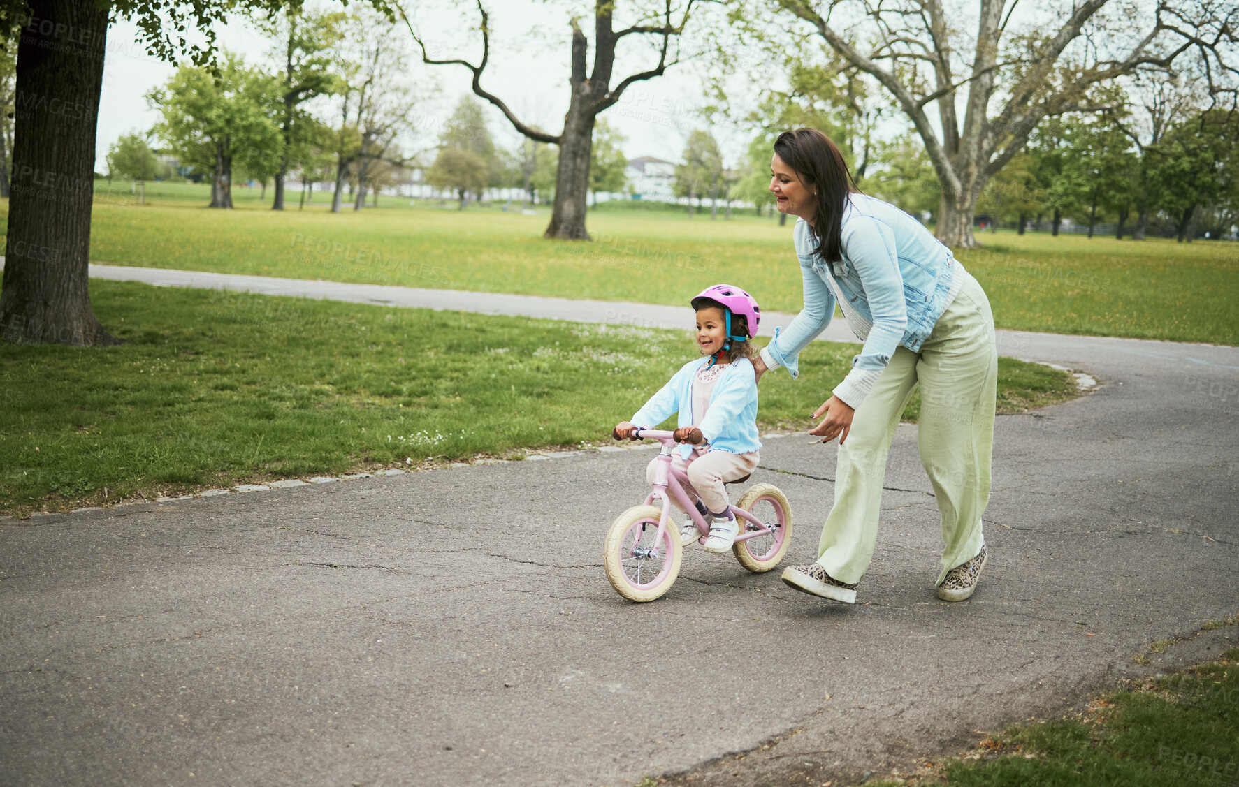 Buy stock photo Kids, bike and a mother teaching her daughter how to cycle in a park while bonding together as a family. Nature, love and children with a girl learning how to ride a bicycle with her mom outside