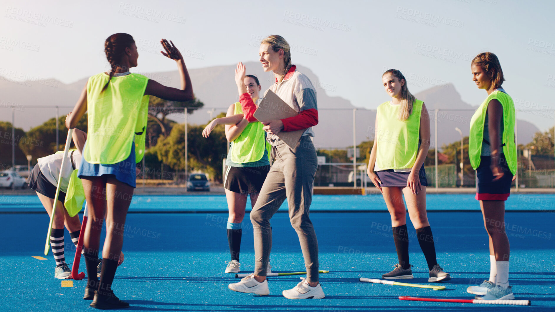 Buy stock photo Hockey, women team with coach and sport, high five and coaching with game strategy, training and fitness on turf outdoor. Athlete stretching, start practice and wellness, motivation and support