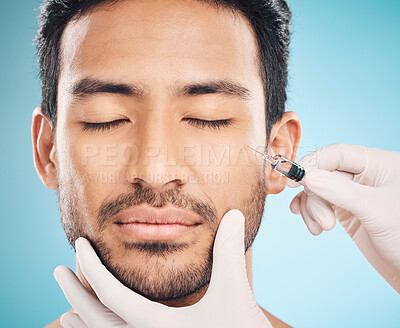 Buy stock photo Face, hands and change with a plastic surgery man in studio on a blue background for beauty enhancement. Aesthetic or prp with a young male patient eyes closed in a clinic for skincare closeup