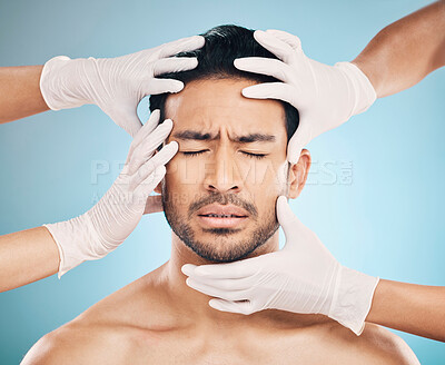 Buy stock photo Face, hands and plastic surgery with a nervous man in studio on a blue background for beauty enhancement. Aesthetic and change with a young male patient eyes closed in a clinic for skincare