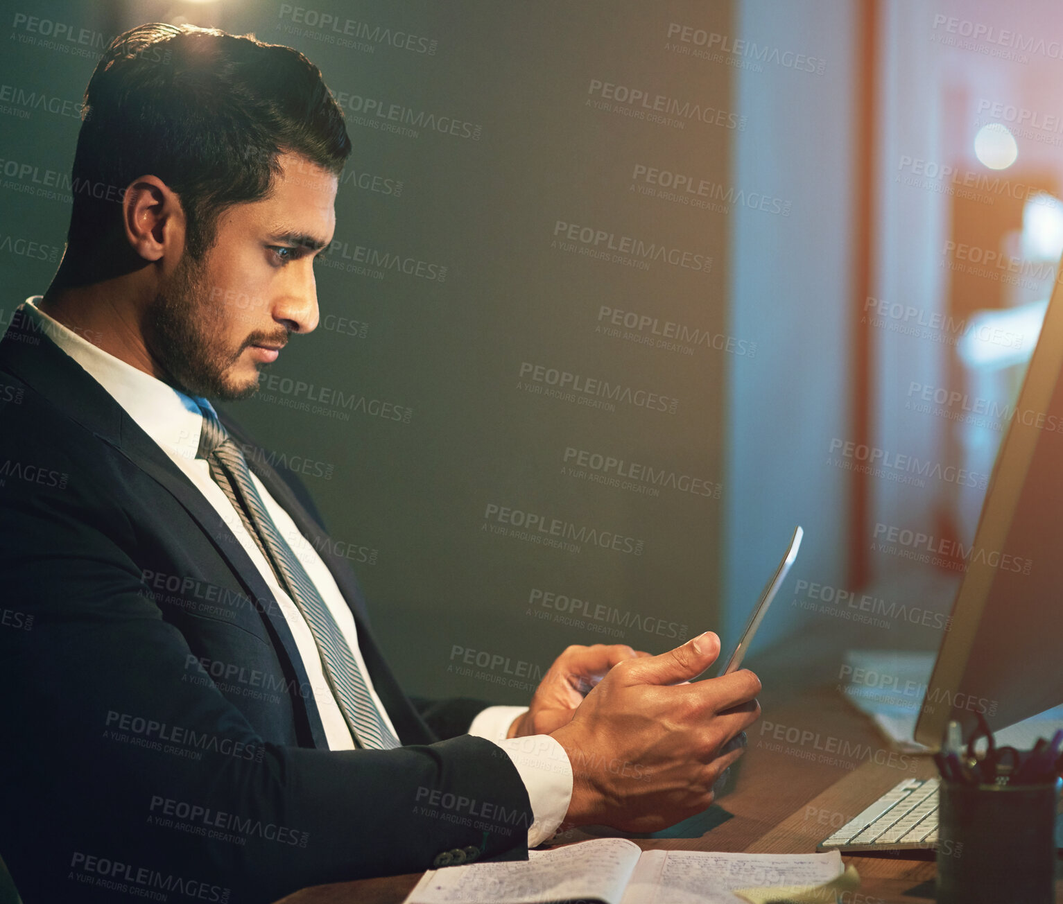 Buy stock photo Businessman, office and phone by desk at night for career, advocate or lawyer with research. Male person, computer and mobile by table for work at law firm, plan for justice or court with technology