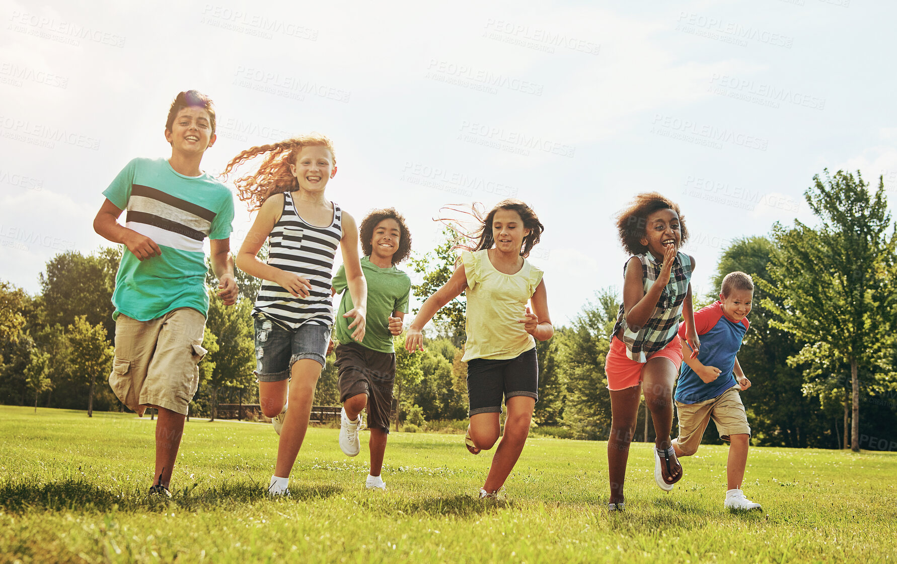 Buy stock photo Happy kids, playing and running with grass field in nature for fun, playful day or sunshine at park. Diversity or group of excited children or youth enjoying sunny outdoor holiday or weekend together