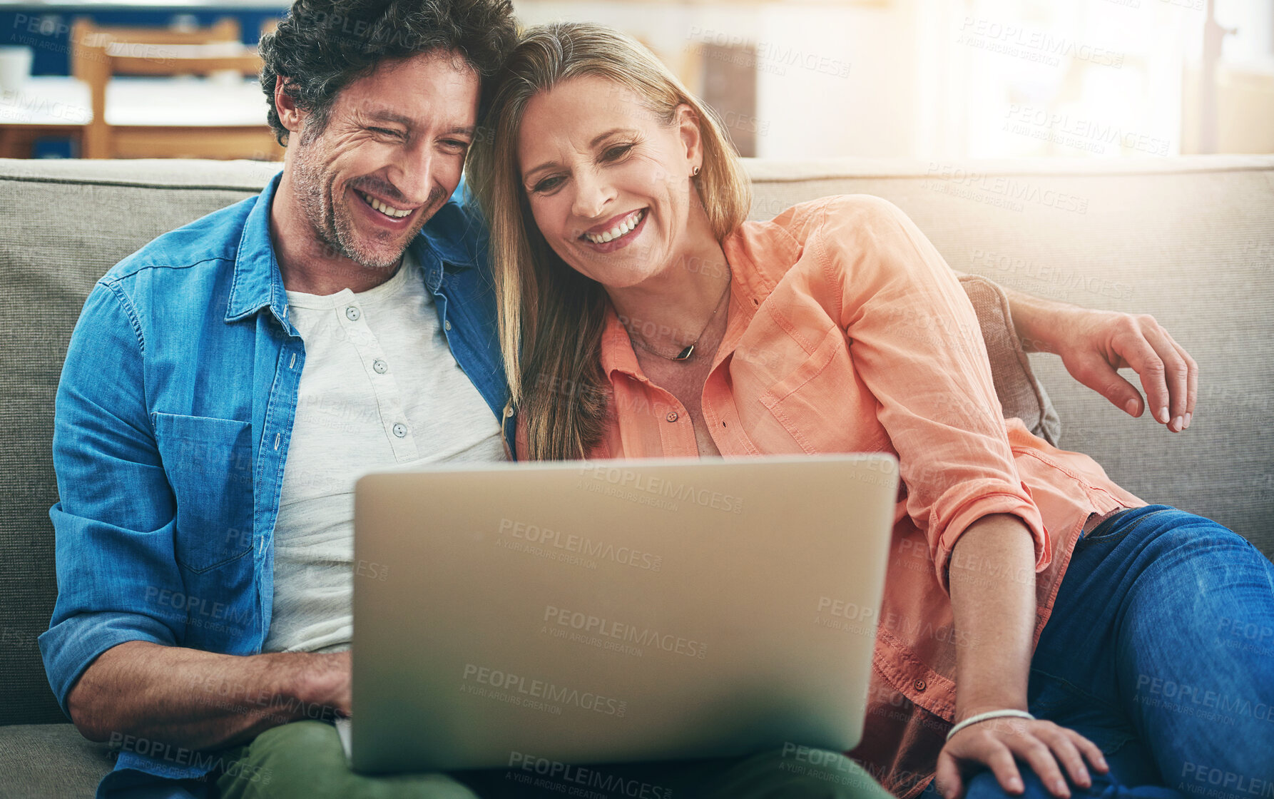 Buy stock photo Mature, couple and laughing with laptop in home for comedy movie, funny series or streaming service on sofa. People, technology and comic video on couch with relax, embrace or entertainment in lounge