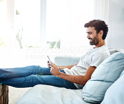 Buy stock photo Home, man and tablet on sofa for networking, chat and online conversation with contact. Living room, male chatter and mobile app for streaming movies, games and social media with technology to relax