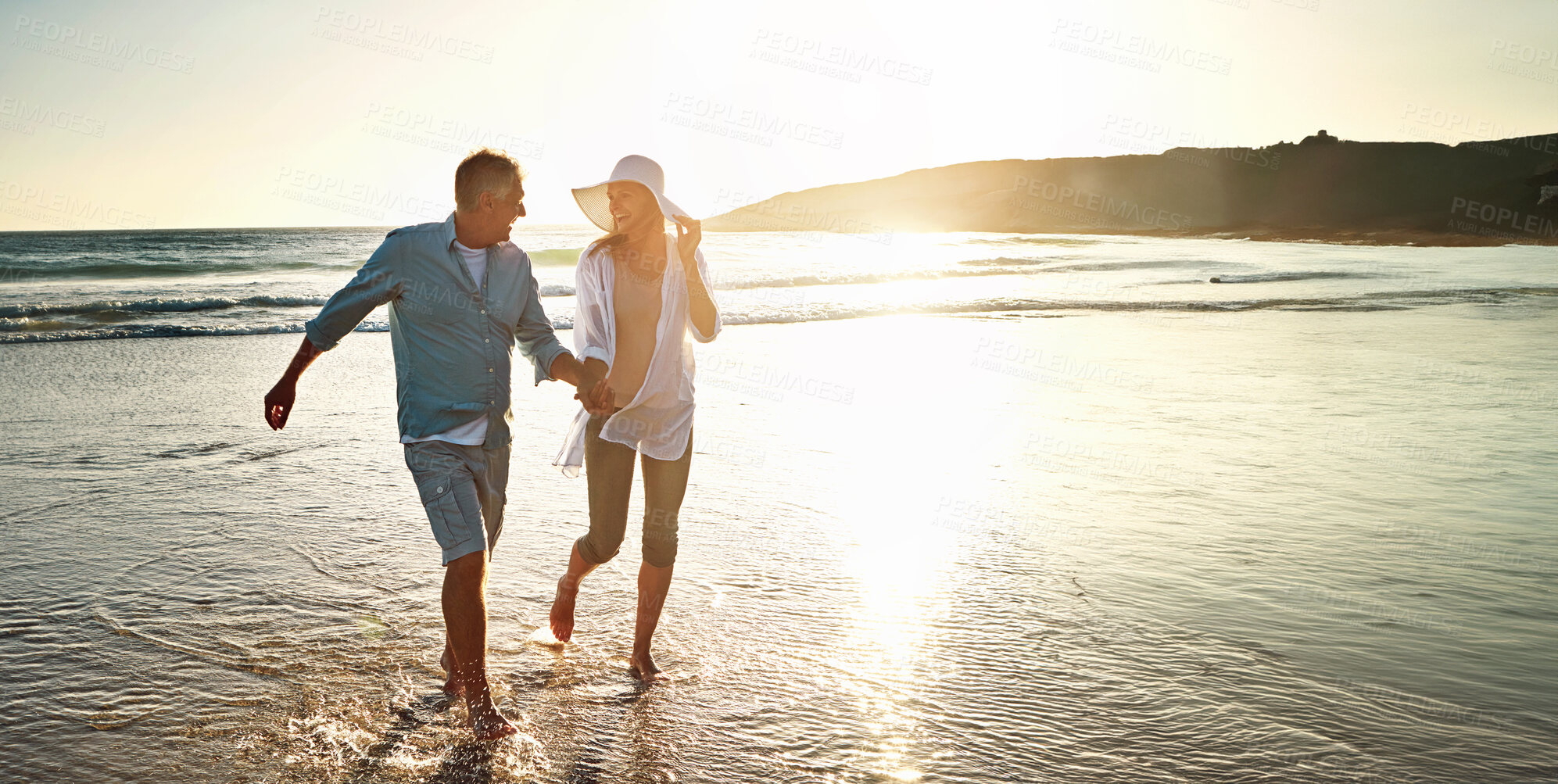 Buy stock photo Happy couple, walking and beach for holiday on island or coast for getaway, travel and vacation in Bali. Woman, man and holding hands for love or marriage anniversary by ocean at sunset in Indonesia