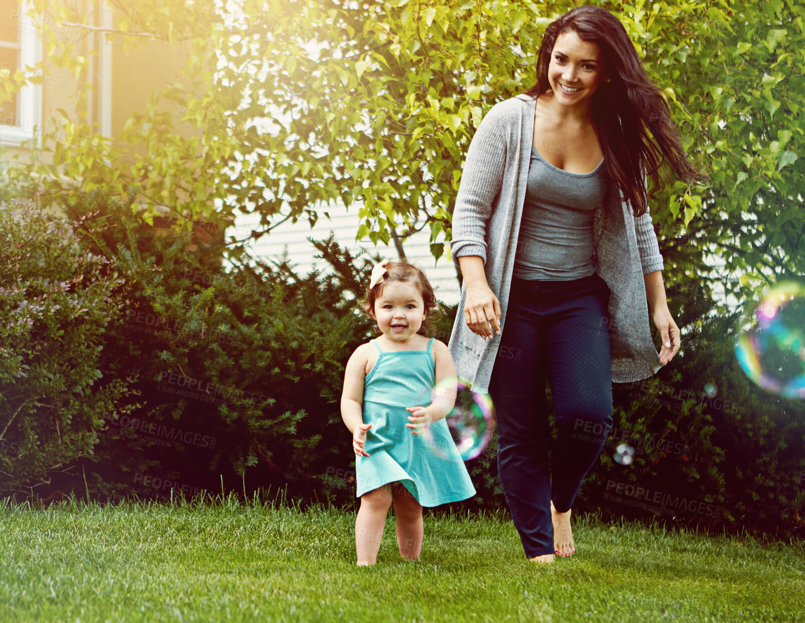 Buy stock photo Mom, girl and happy with bubbles in garden for games, running or playful with bonding at family house. Child, mother and daughter with soap, smile or care with love for connection on lawn in backyard