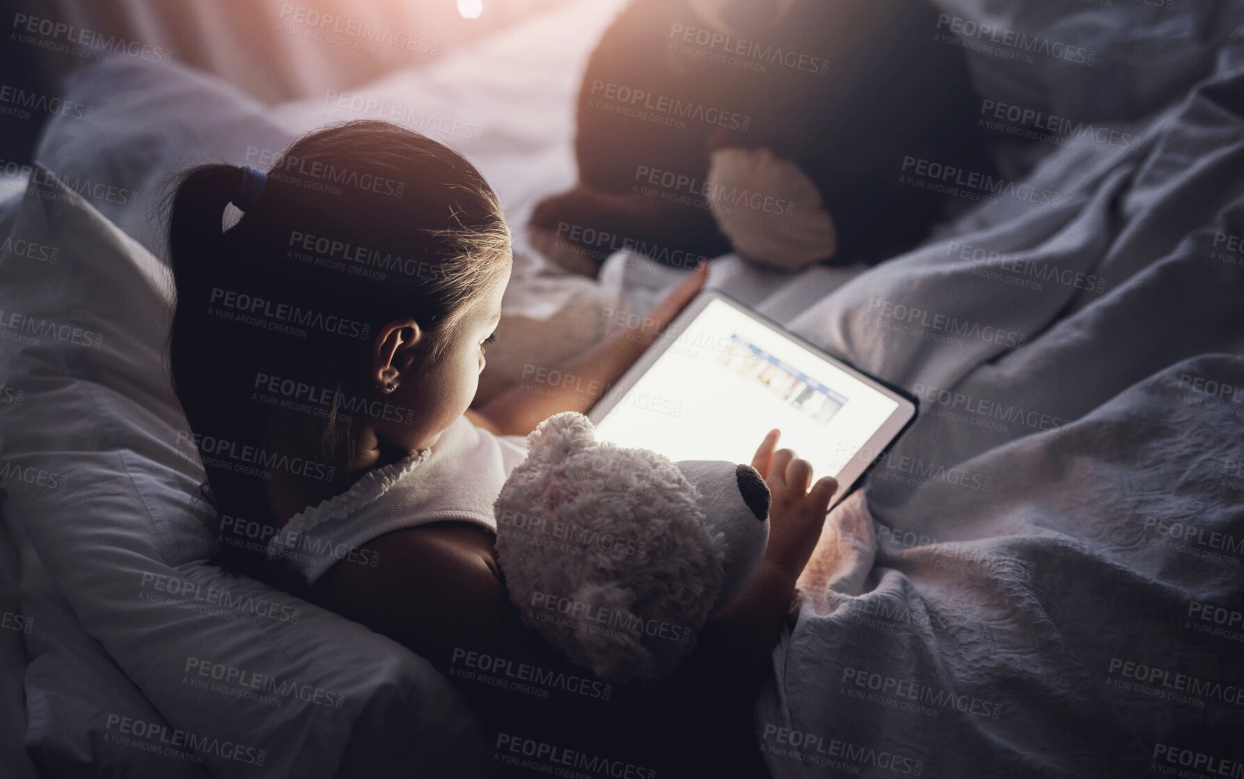 Buy stock photo Tablet, reading and kid at night with ebook, story and youth game with cartoon and language app. Tech, teddy bear and young girl with scroll, relax and evening screen time at home in bed online